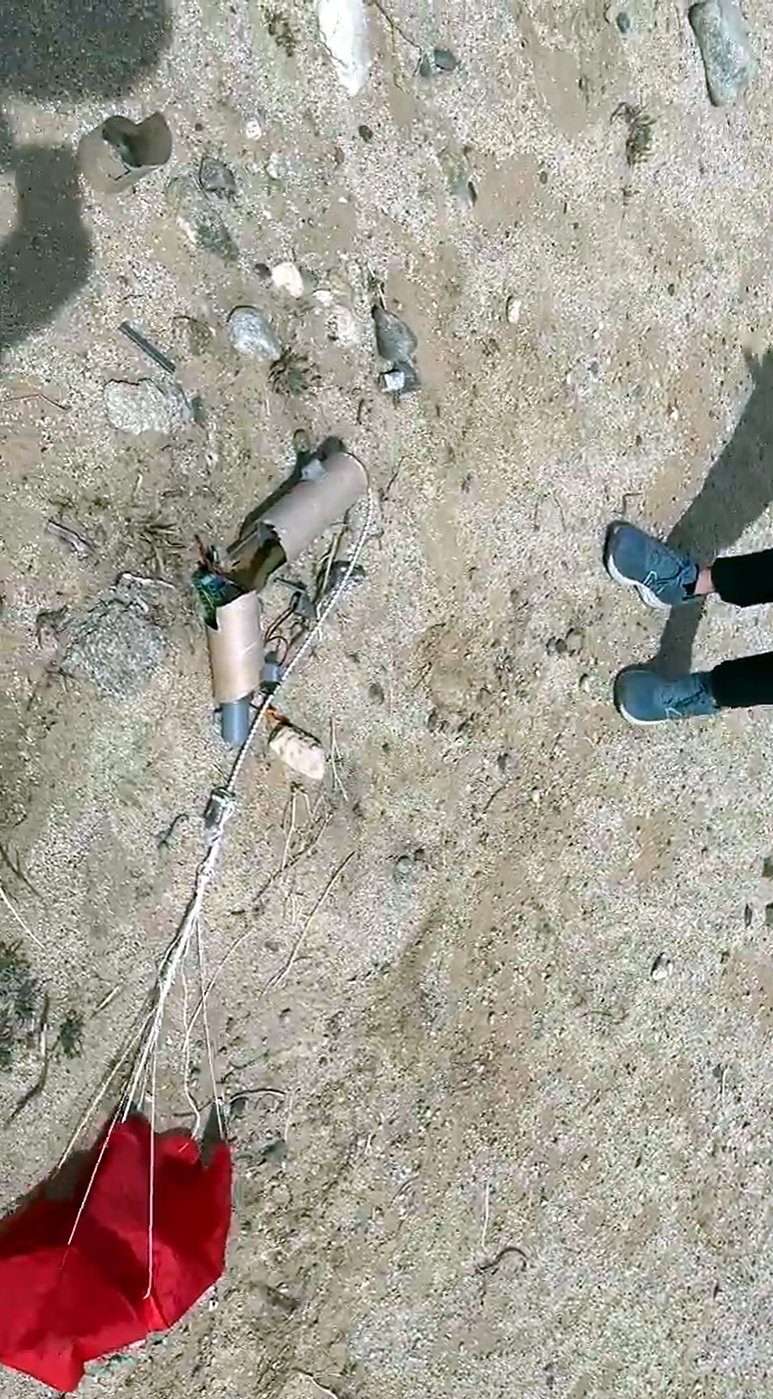 The rocket on the ground after launch two, parachute beside it