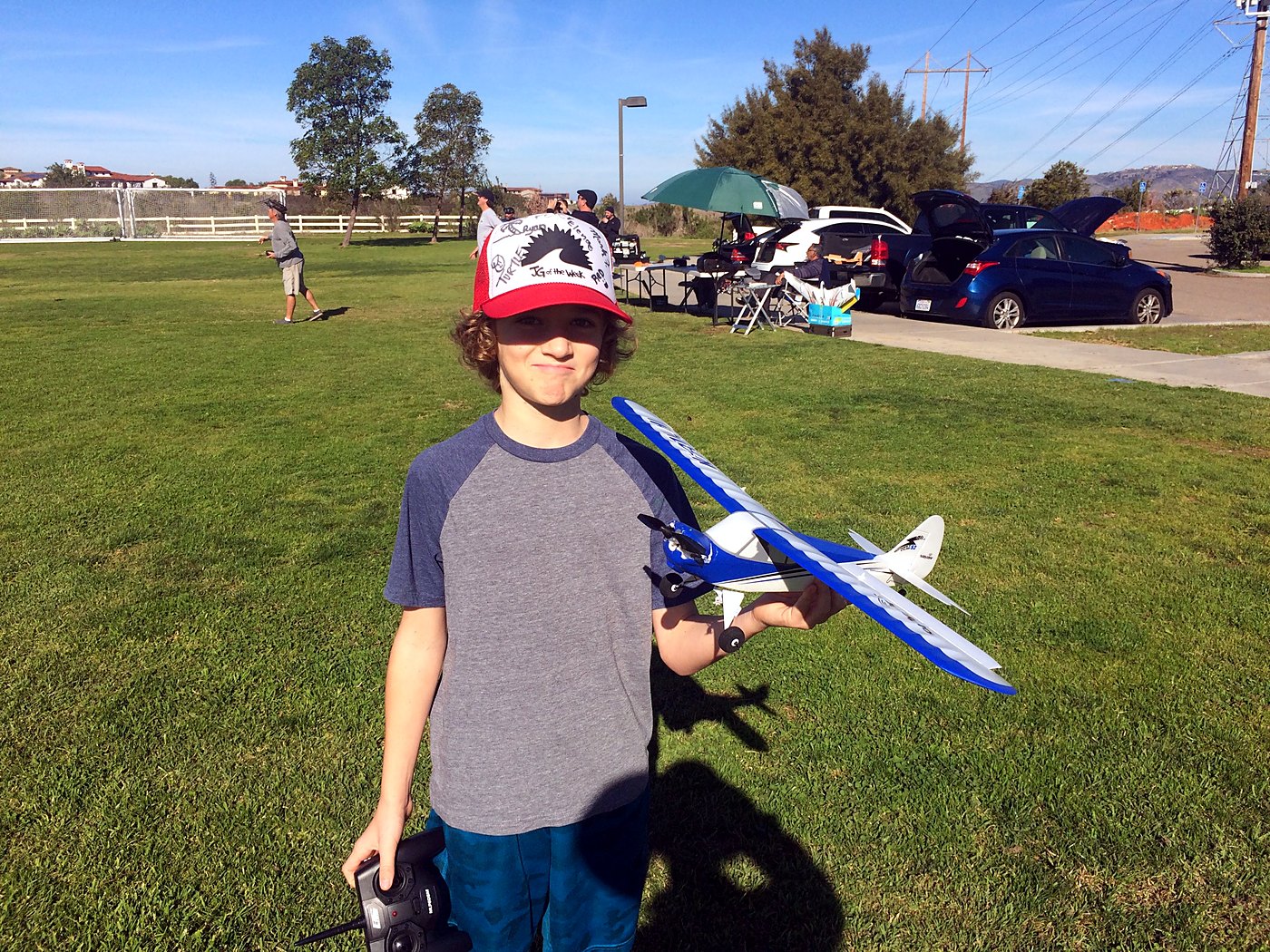 Holding my first RC plane, a blue and white high-wing model, in a park