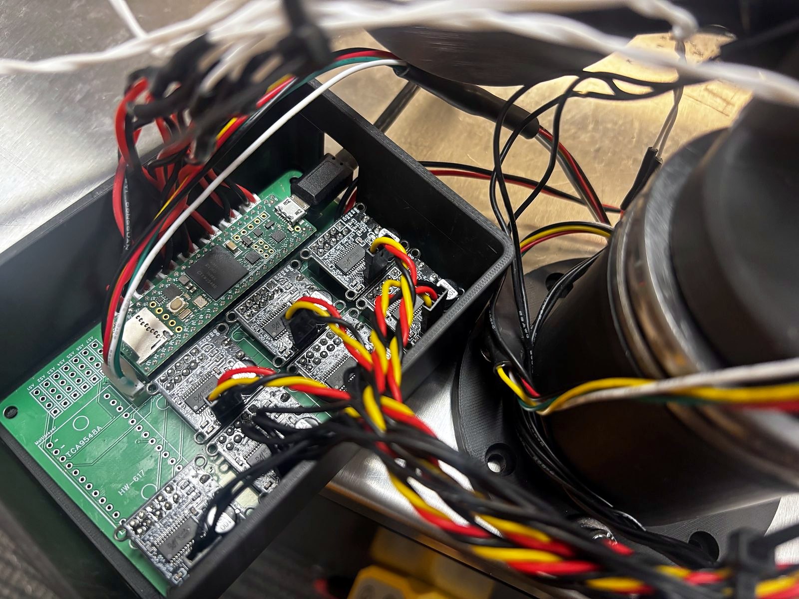 The populated controller board in its printed enclosure, a Teensy and driver modules plugged in, motor wiring running out to the joints