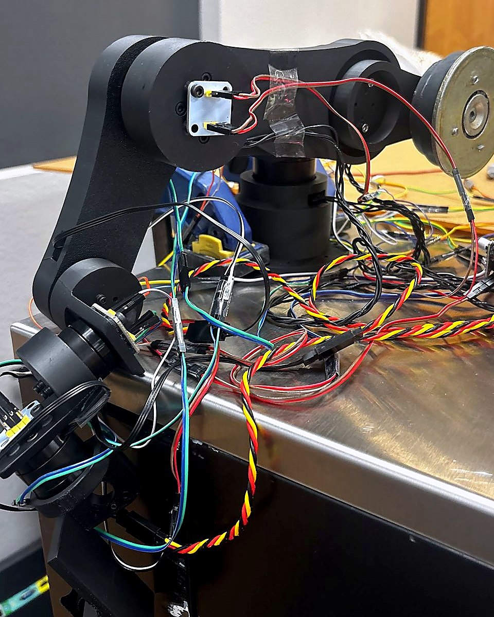 The six-degree-of-freedom haptic master arm on a bench, wiring running out to its driver electronics